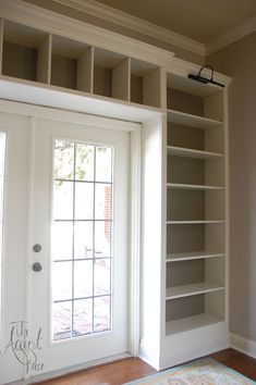 an empty room with open bookcases and a door leading to the front porch