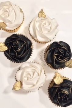 four cupcakes with black and white frosting roses on them are arranged in a circle