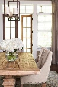 a dining room table with chairs and flowers in a vase on it's centerpiece