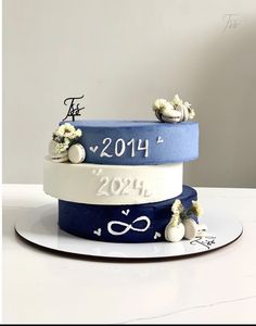 three tiered cake decorated with white and blue ribbons on top of each other in the shape of numbers