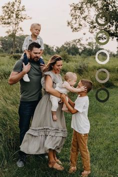 a family standing in the grass holding their children