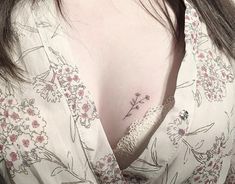 a close up of a woman's breast with flowers on her chest and an arrow tattoo