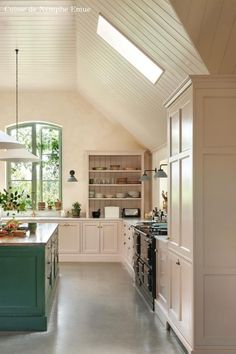 a large kitchen with an island in the center and skylights above it, is shown