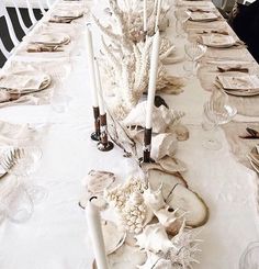 the table is set with plates, candles and seashells for an elegant dinner