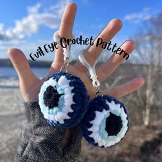 the hand is holding two blue and white crocheted eyeballs on it