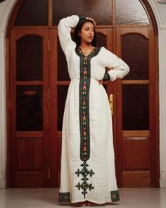 This Habesha Kemis is a true work of art, crafted from handwoven Axum fabric that showcases the rich cultural heritage of Ethiopia. The intricate patterns and vibrant colors of the fabric are a testament to the skill and artistry of the weavers, creating a mesmerizing and eye-catching effect. The dress is expertly crafted with intricate details that highlight the beauty of the wearer, from the flowing sleeves to the elegant neckline. The simple and elegant design of the dress allows the handwove Traditional Long Handloom Dress, Traditional Pattern Dresses For Rituals, Traditional Dresses With Multicolor Embroidery And Woven Motifs, Traditional Long Sleeve Habesha Kemis, Traditional Festive Dress With Weaving Work, Multicolor Handloom Dress With Traditional Drape, Traditional White Handwoven Dress, Traditional Long Sleeve Dress With Weaving Work, Ceremonial Dresses With Weaving Work For Festivals