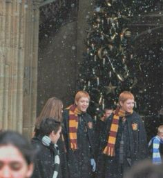 two harry potters are standing in front of a christmas tree while people look on