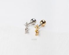 three pairs of gold, silver and diamond ear studs on white fabric with space for text