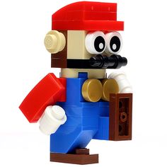 a lego man with a red hat and blue shirt holding a brick in his hand