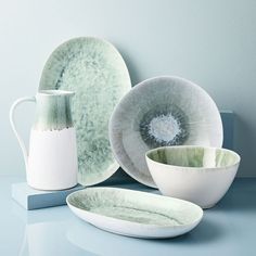 there are plates, cups and vases sitting on the counter top next to each other