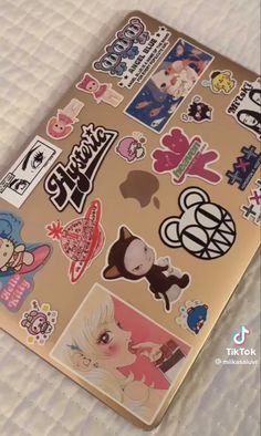 a laptop covered in stickers on top of a bed