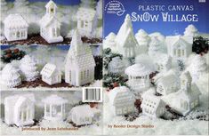 plastic canvass snow village book with white houses and trees in the snow, surrounded by pine cones