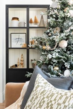 a living room with a christmas tree in the corner and other holiday decorations on shelves