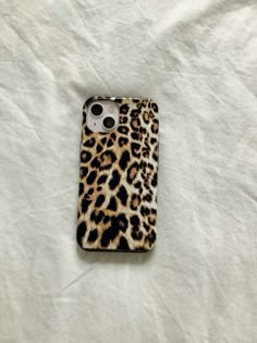 an iphone case with a leopard print pattern on the front and back cover is laying on a white sheet