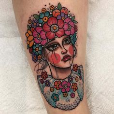 a woman's face with flowers on her head is shown in this tattoo design