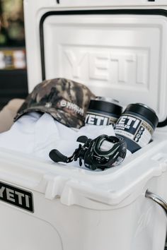 fishing gear in a cooler with hat and other items inside the bins on display