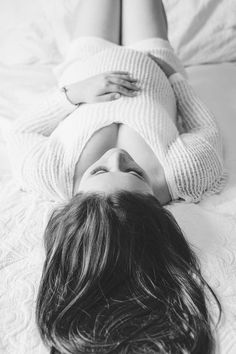 a black and white photo of a woman laying on a bed