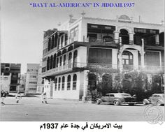 an old black and white photo of a building with cars parked in front of it