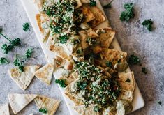 nachos on a white plate topped with cheese and herbs