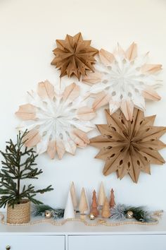 three wooden snowflakes mounted on the wall above a white dresser and christmas tree