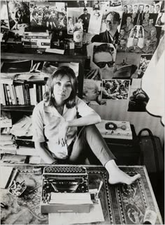 a woman sitting on top of a desk next to a pile of books