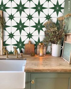 a kitchen with green and white tiles on the wall next to a sink in front of a window