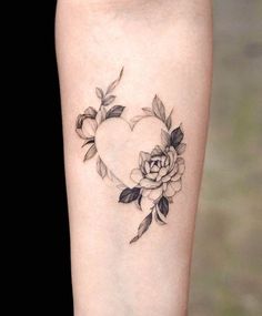 a heart shaped tattoo with flowers and leaves on the side of the leg, in black ink