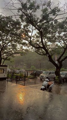 a motor scooter is parked in the middle of a parking lot as it rains