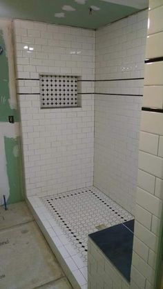 a white tiled shower stall with black and white tiles on the floor, walls and ceiling