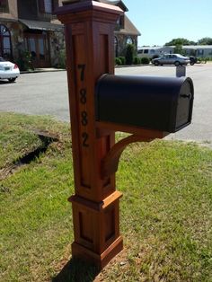 a wooden post with a mailbox attached to it in the grass near a street