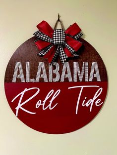 a red and white sign that says roll tide with a bow on it's side