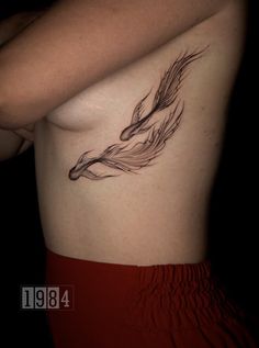 a woman's breast with an artistic tattoo design on her left side ribcage