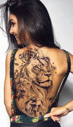 a woman with a lion tattoo on her back is standing in front of a wall