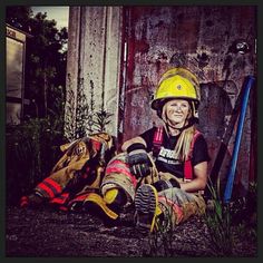 a woman wearing a fireman's helmet sitting on the ground in front of a building