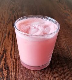 a pink drink sitting on top of a wooden table