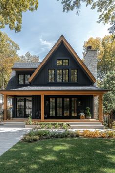 a black and brown house with lots of windows on the front porch, grass area and trees