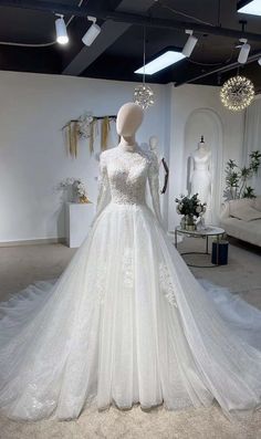 a white wedding dress on display in a room with chandeliers and other decorations