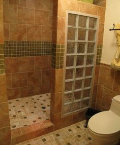 a bathroom with tiled walls and a glass shower door in the corner, next to a toilet