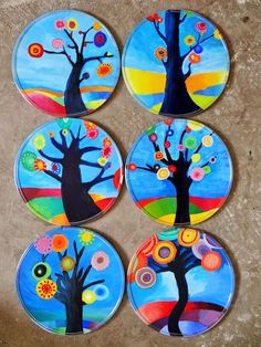 four colorful plates with trees painted on them