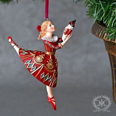 a christmas ornament hanging from a tree with a ballerina holding a nutcracker