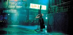 a person holding an umbrella on a rainy night in the city with buildings and neon lights