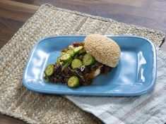 a blue plate topped with a sandwich and cucumbers