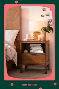 a nightstand with books on it next to a bed