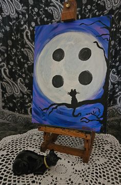 a painting on an easel with a black cat sleeping in front of the moon