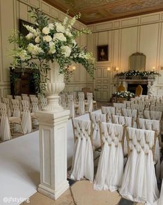 a room filled with lots of white chairs covered in white cloths and sashes