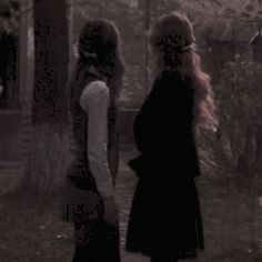 two women standing next to each other in the woods