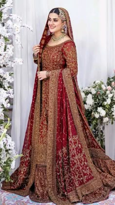 a woman in a red and gold bridal gown standing next to a fire place