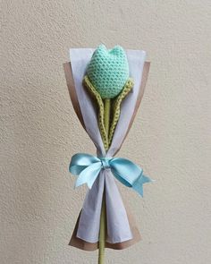 a crocheted flower with a blue bow on it's head is wrapped in white paper