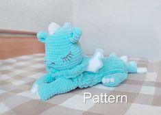 a blue crocheted stuffed animal laying on top of a checkered tablecloth