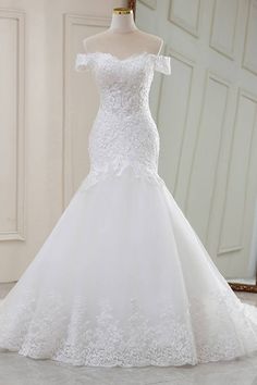 a white wedding dress on display in front of a mirror with an ornate frame behind it